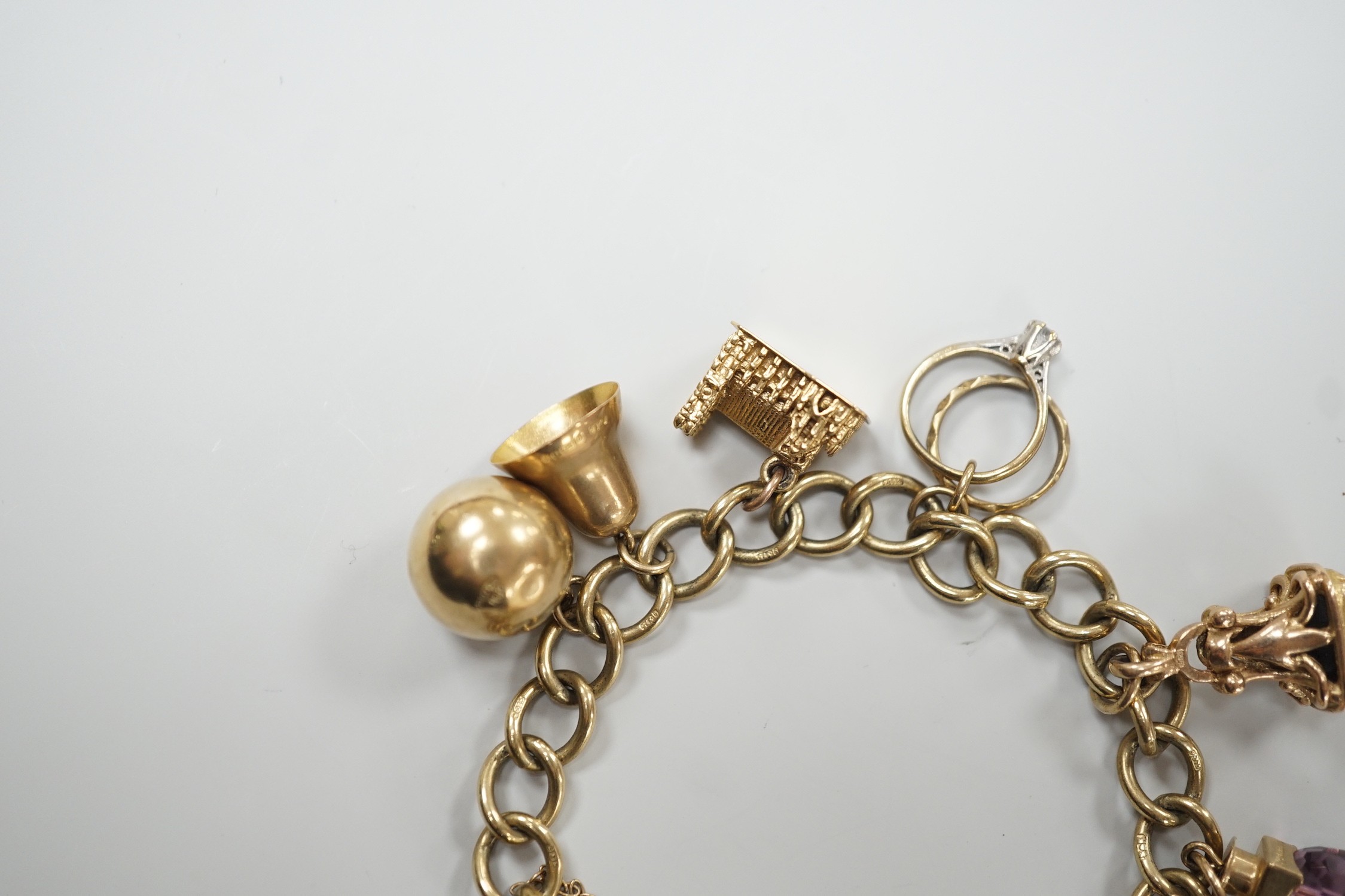 A 9ct gold oval link charm bracelet, hung with ten assorted charms including nine 9ct gold, gross weight 31.9 grams.